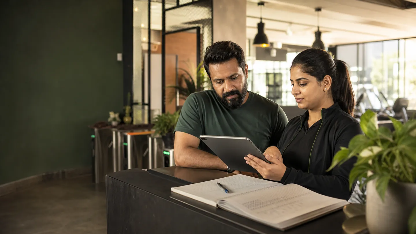 Indian gym owner comparing gym management software on mobile and desktop